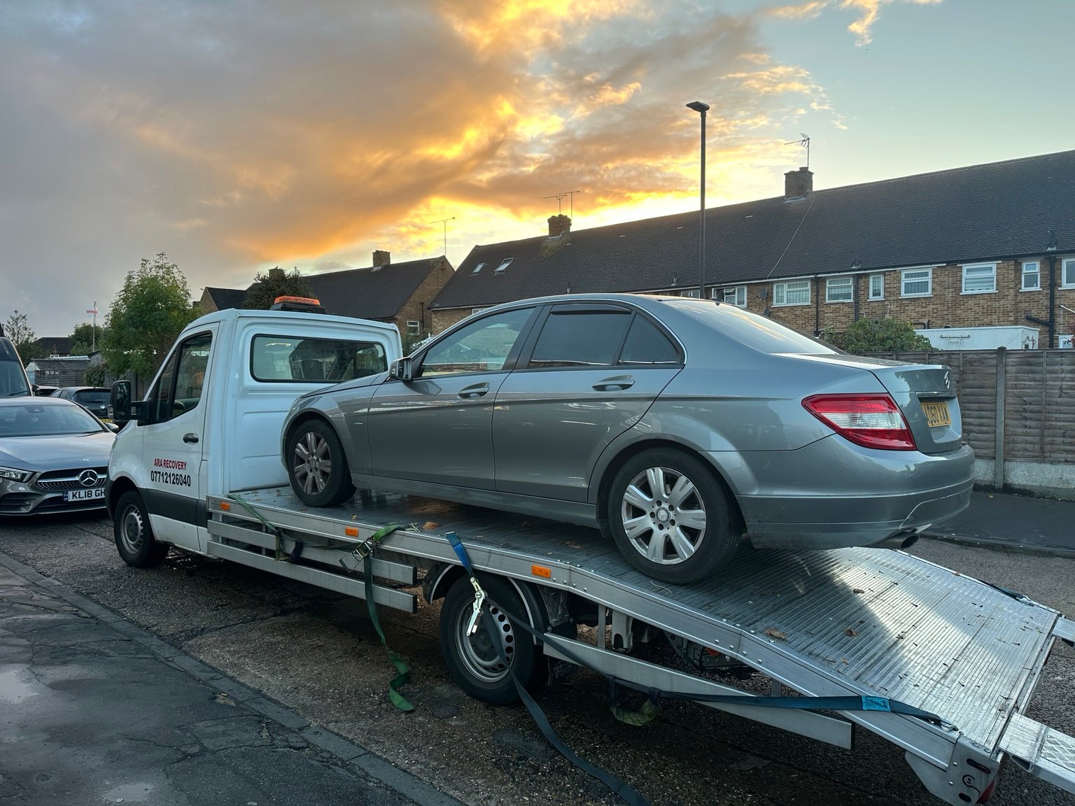 ARA Recovery truck transporting a silver Mercedes at sunset