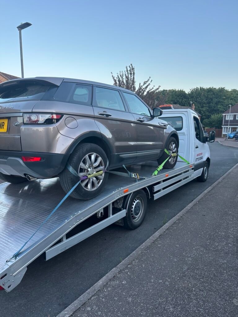 Grey SUV secured for transport on a recovery truck