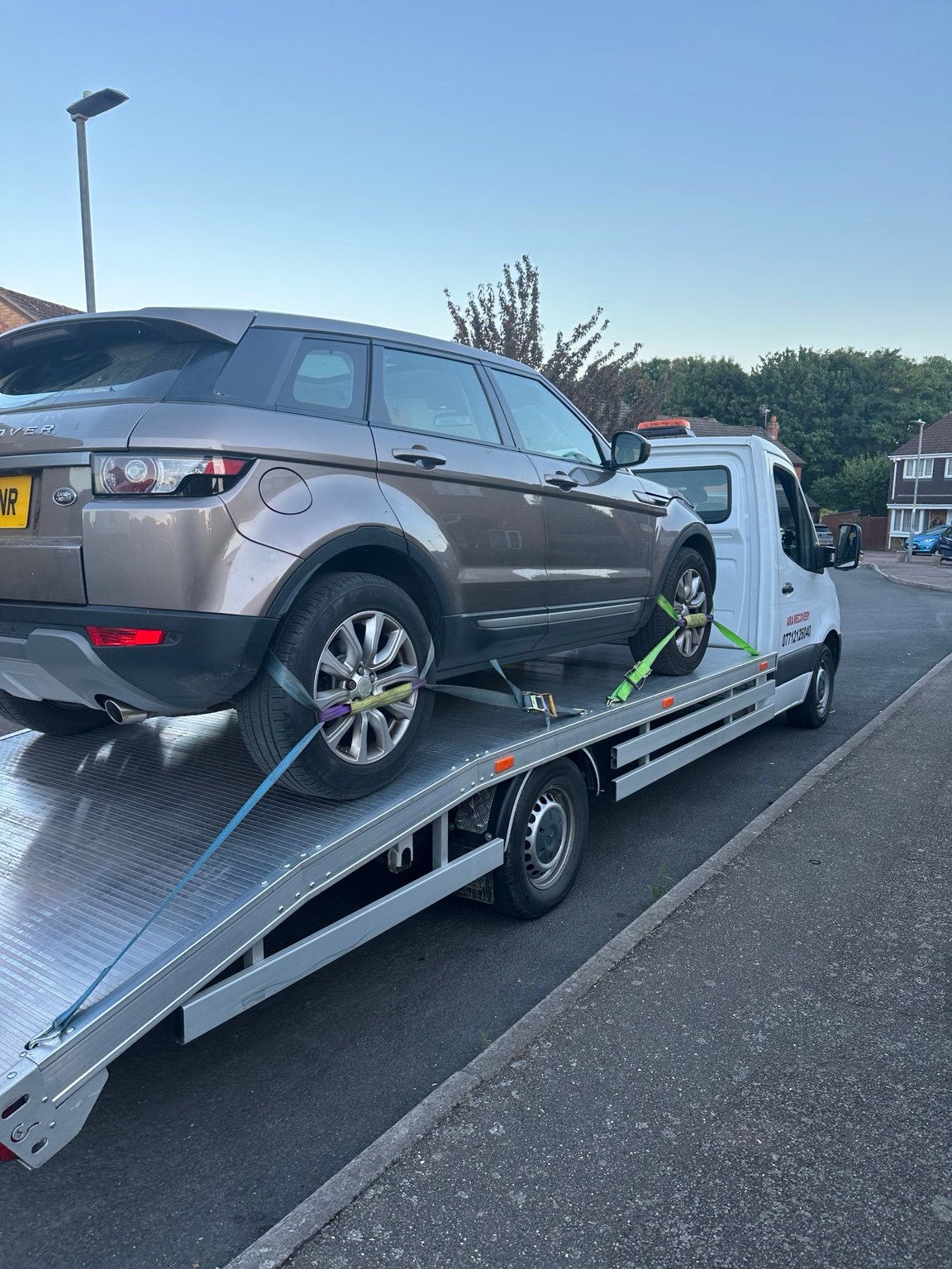 Grey SUV secured for transport on a recovery truck